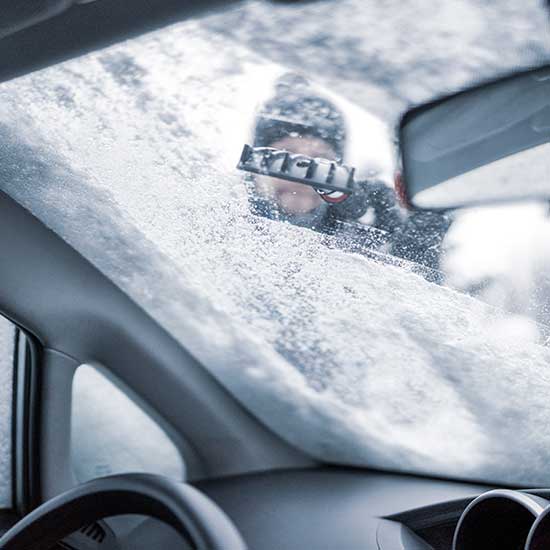 Mann kratzt im Winter die Windschutzscheibe frei
